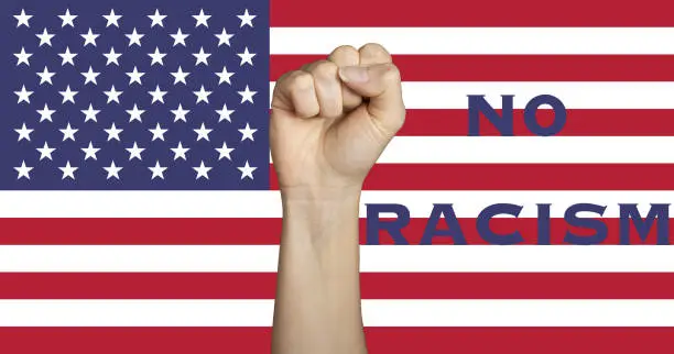 A fist raising up to support the no racism movement against a USA flag background