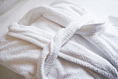 White Bathrobe on bed in bedroom, close-up. The concept of rest in a hotel.