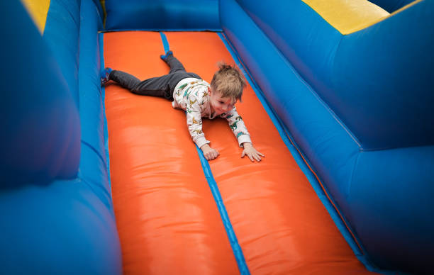istock Happy little boy sliding down on a bouncy castle 1254205618
