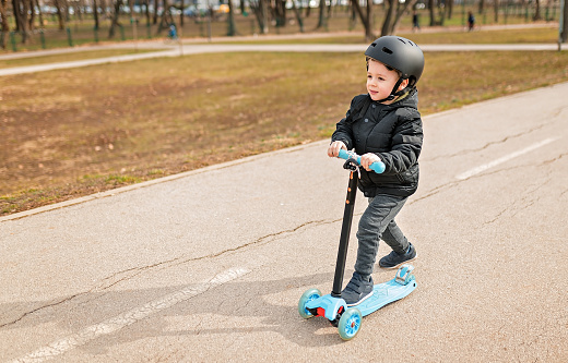 Small boy riding on the scooter in the park