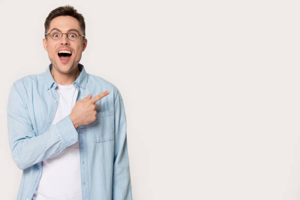 istock Surprised young man showing by forefinger at blank copy space 1254205841