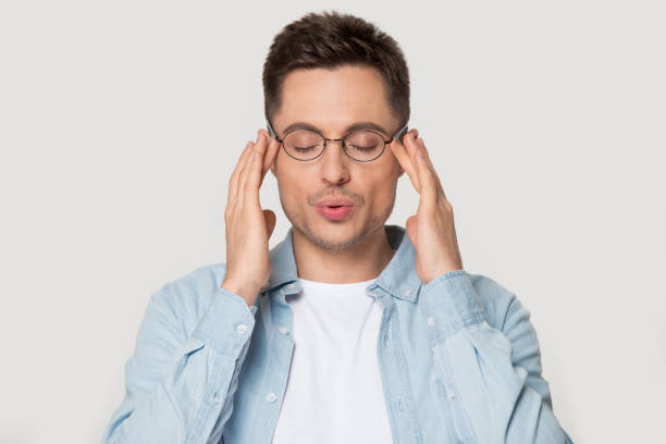 Young caucasian man in eyeglasses massaging temples.