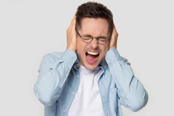 istock Stressed young man in eyeglasses annoyed by loud sound. 1254205876