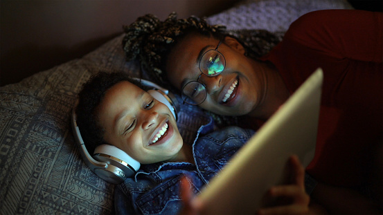 Siblings listening music using digital tablet at bed