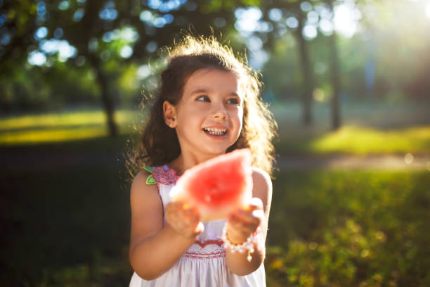 istock Funny kid eating watermelon outdoors in summer park, 1254210697
