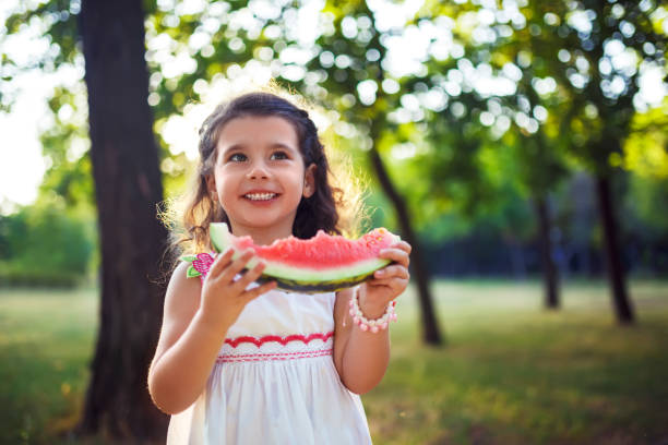 istock Funny kid eating watermelon outdoors in summer park, 1254210712
