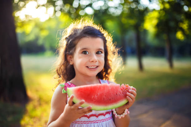 istock Funny kid eating watermelon outdoors in summer park, 1254210738