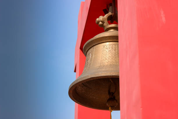 A Mammoth Brass bell with red color columns against the dark blue sky outside a Jain digambara temple in the pilgrimage town of Parasnath hills in Jharkand state of India.