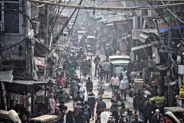 Crowd, rickshaws and fog pollution in a busy road in Old Delhi, India. \nPhoto taken from Jama Masjid.
