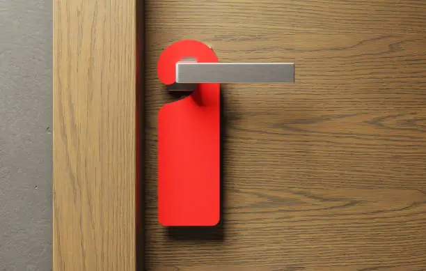 Hotel door with red empty sign "do not disturb" on a door handle.