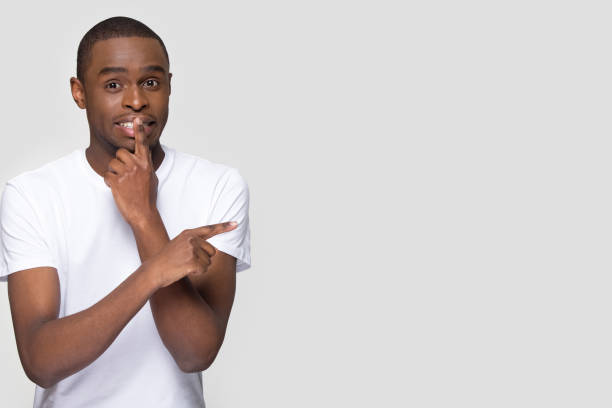 istock African American man pointing finger at copy space, secret information 1254214838