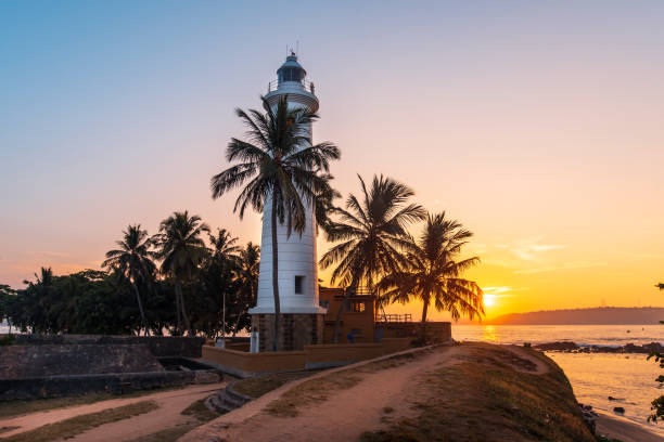 Sunrise over Galle Dutch Fort Lighthouse surrounded by coconut trees in Sri Lanka Sunrise over Galle Dutch Fort Lighthouse surrounded by coconut trees in Sri Lanka, one of the most popular travel spots in the south of the country sri lanka pattern stock pictures, royalty-free photos & images