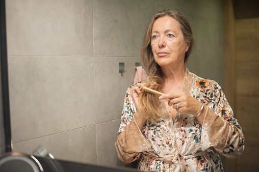 Mature Woman Combing Her Long Hair in Domestic Bathroom