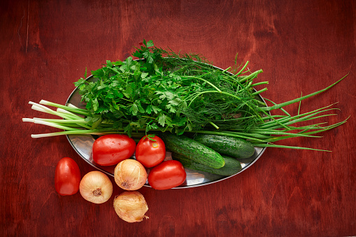 healthy food - fresh vegetables and greens on a wooden background, greens, onion and tomatoes