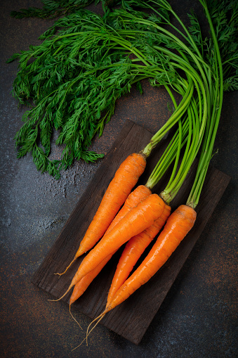 Raw fresh carrots on  dark background. Selective focus.Top view. Copy space.Vegetarian food concept.