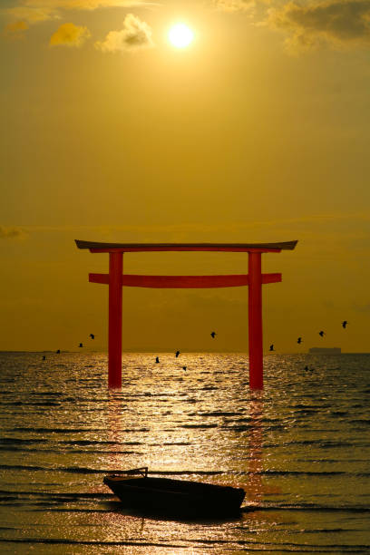 istock reflection torii sunset orange cloud on the sky and birds flying on the sea vertical view 1254220765