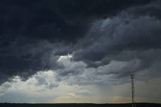 Cell tower on a background of a stormy sky. Light in a thundercloud