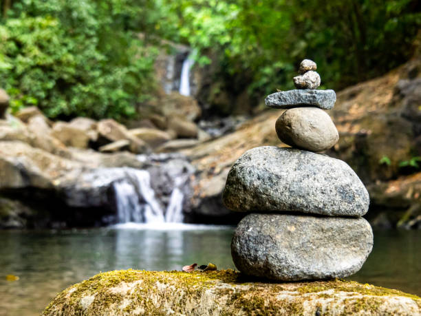 Blissful scene of stones perched atop each other, signifying inner peace and tranquility. A waterfall flows down in the background. Taken in Uvita, Costa Rica