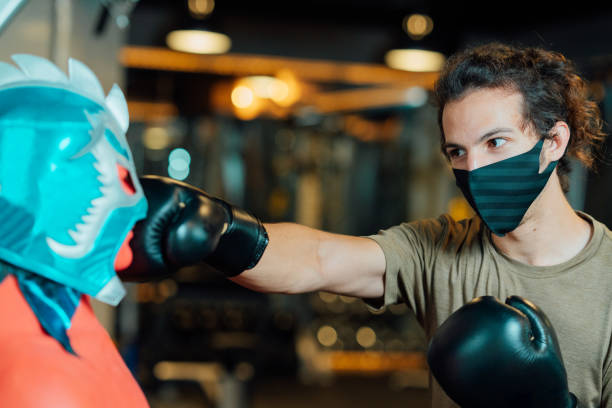 istock Young athlete training boxing in gym while wearing protective face mask 1254231478