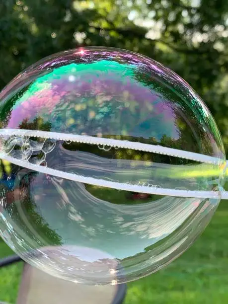 A close up picture of a bubble with trees in the background.