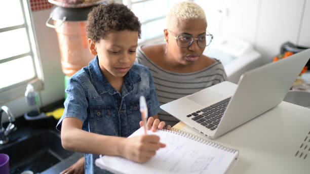 Mother helping her son studying with laptop on a online class at home Mother helping her son studying with laptop on a online class at home homeschooling photos stock pictures, royalty-free photos & images
