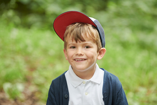 4 years old boy having a great time having fun in public park. Trees all around him