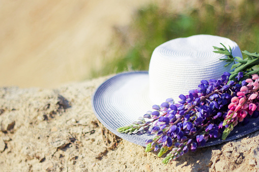 hat with lupins. Hat near a bouquet of lupine flowers. Concept summer picnics. hat decorated with bouquet flowers. rustic style home decor