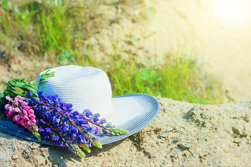 Hat near a bouquet of lupine flowers. Concept summer picnics. hat decorated with bouquet flowers. hat with lupins. rustic style home decor