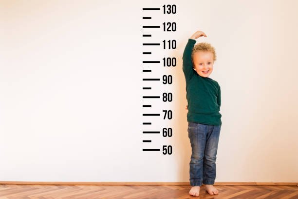 istock Little boy measuring height near white wall. Copy space 1254241543
