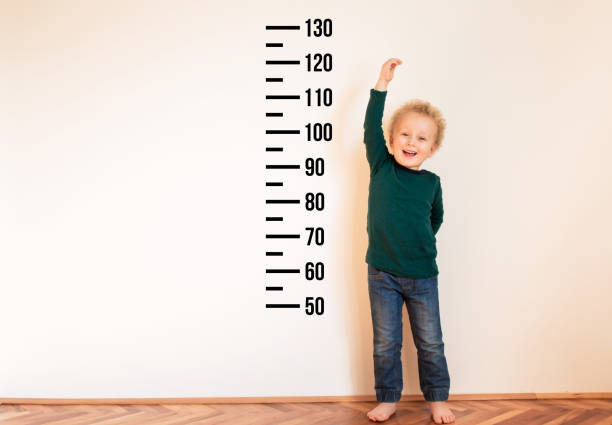 istock Little boy measuring height near white wall. 1254241638