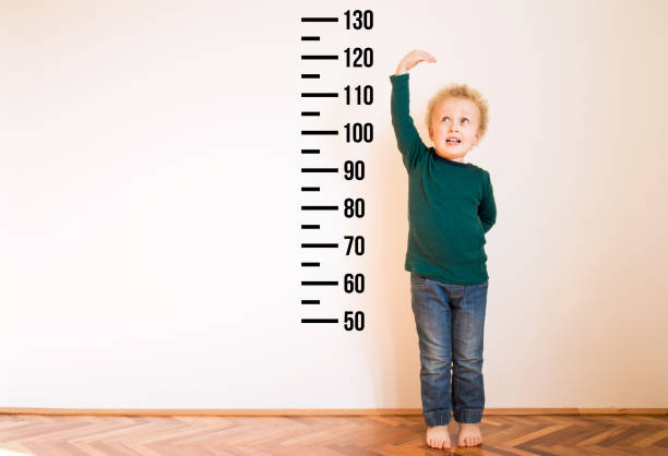 istock Little boy measuring height near white wall. Copy space 1254241870