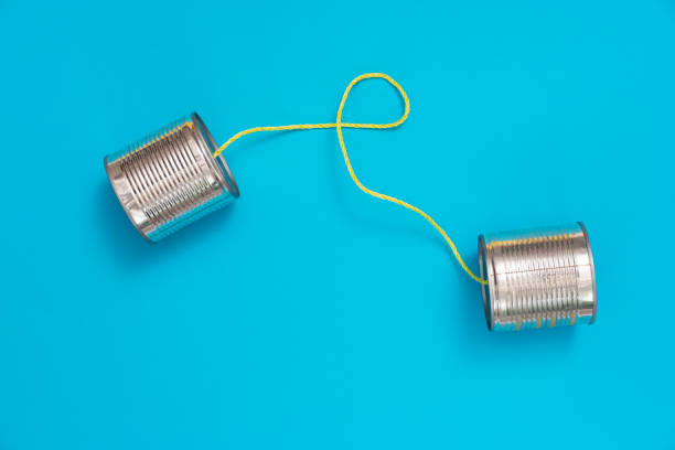 téléphone de boîte d’étain sur le fond bleu de papier - communication connection can tin can phone photos et images de collection