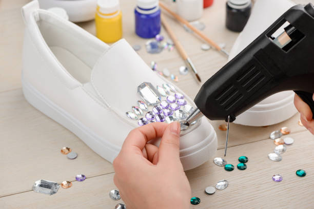 istock Girl decorating her shoes with different rhinestones using a hot glue gun 1254246550