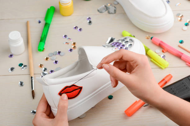 istock Designer sewing embroidered lips badge to a white sneaker 1254247012