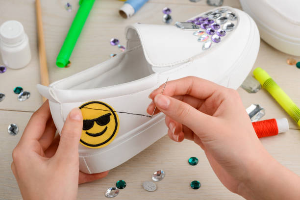 istock Women customizing daughter's slip-on shoes with rhinestones and smile patch 1254247076