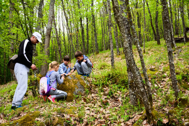 A side view of father with children walking in an spring forest.