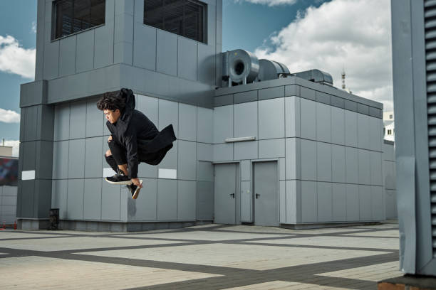 Stylish guy in black outfit making jump in the air while spending time outdoors