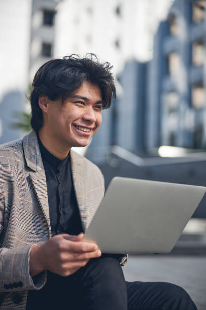 istock Cheerful young man using notebook on the street 1254250635