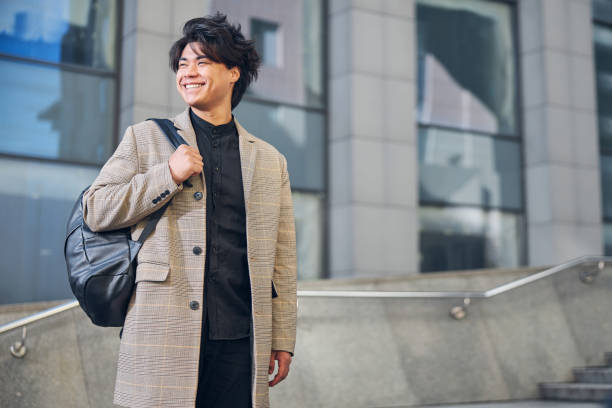 istock Cheerful young man with backpack standing on the street 1254250700