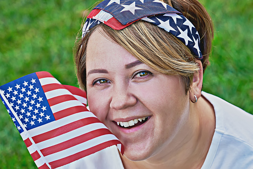 Portrait of smiling caucasian woman in bandana with an American flag during celebration 4th July Independence day