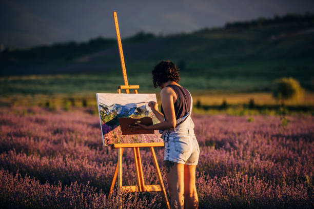 female painter painting on lavender field in sunset - women artist painting easel imagens e fotografias de stock