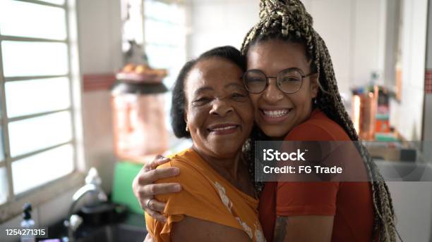 Portrait Of Grandmother And Granddaughter Embracing At Home Stock Photo - Download Image Now