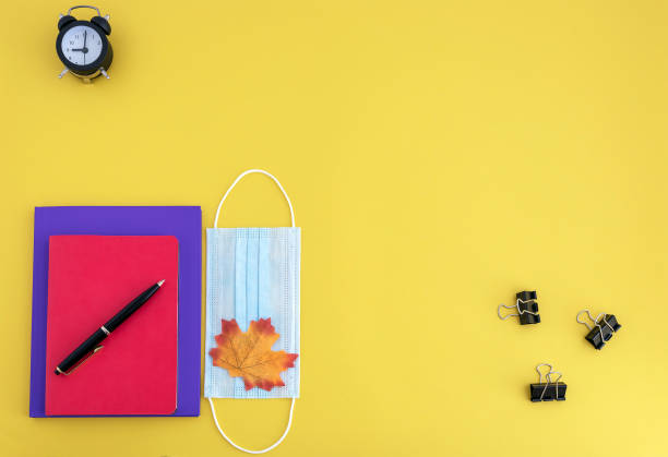 istock workbooks, pen, watch, face mask on yellow background 1254272490