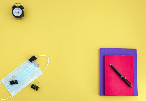 istock workbooks, pen, watch, face mask on yellow background 1254272494