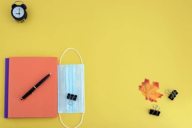 istock workbooks, pen, watch, face mask on yellow background 1254272501