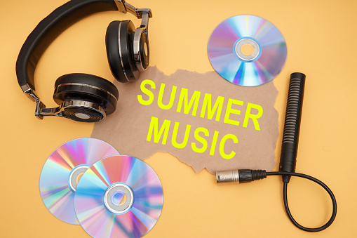 Headphones, microphone and music discs on a yellow background. Inscription SUMMER MUSIC.