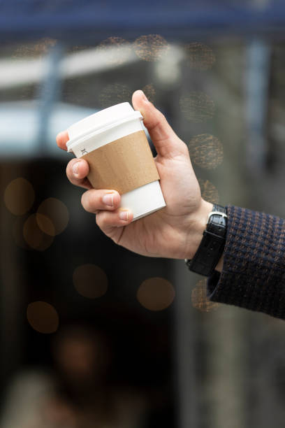 istock A Guy Holding Hot Takeaway Cup with Cafe Background 2 1254280840