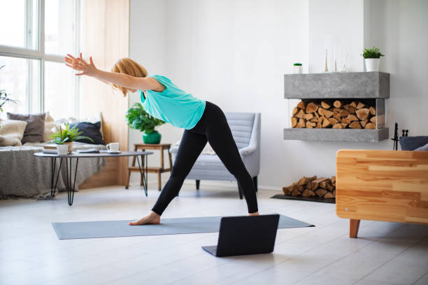 istock Young woman practicing yoga at home with laptop during quarantine 1254288352