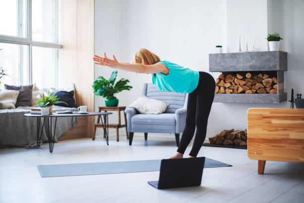istock Young woman practicing yoga at home with laptop during quarantine 1254288387
