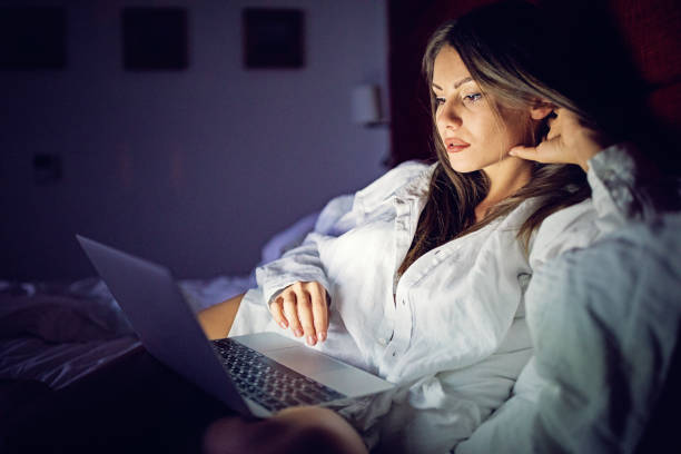 istock Woman is browsing in bed using her laptop 1254288416